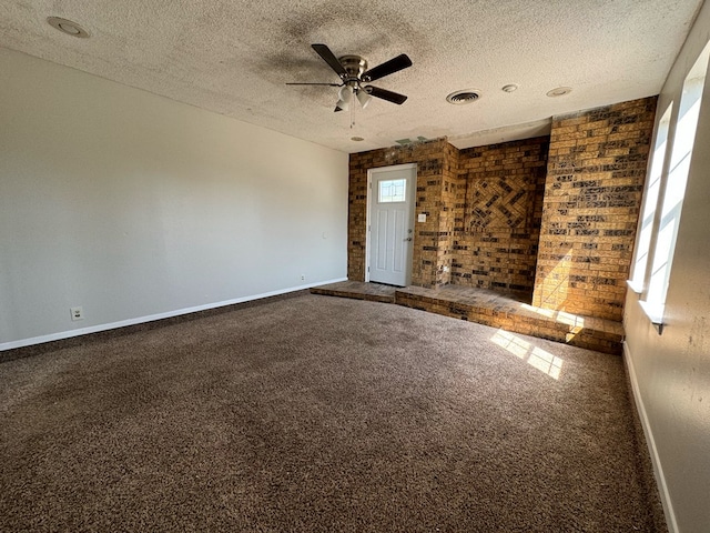 carpeted empty room featuring ceiling fan, a textured ceiling, and brick wall