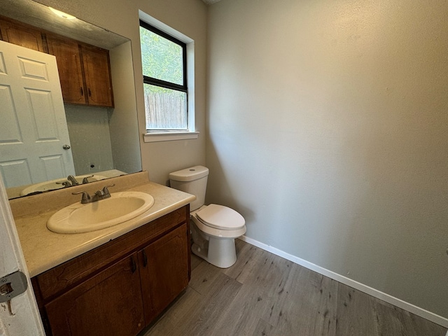 bathroom featuring wood-type flooring, toilet, and vanity