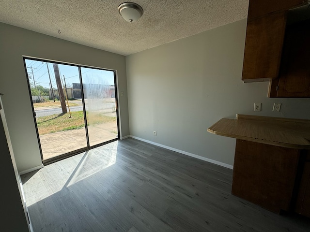 unfurnished dining area featuring dark hardwood / wood-style flooring and a textured ceiling