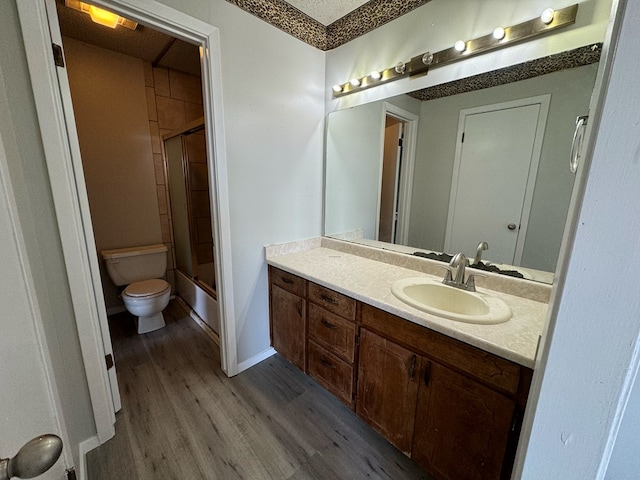 full bathroom with toilet, wood-type flooring, bath / shower combo with glass door, and vanity