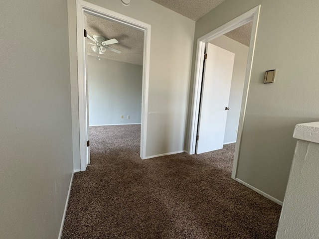 hallway featuring dark carpet and a textured ceiling