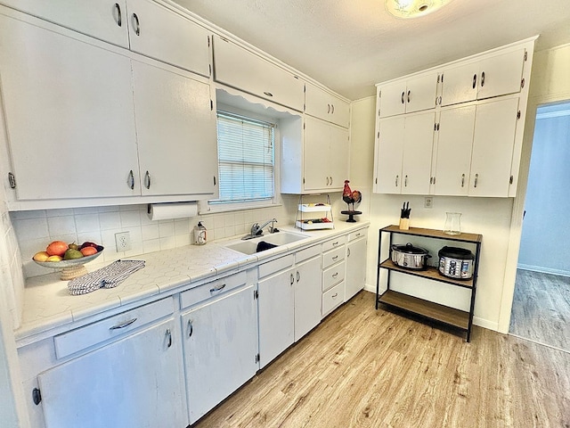 kitchen with white cabinetry, sink, and light hardwood / wood-style flooring