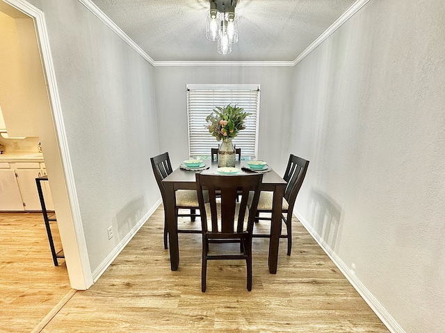 dining space featuring light hardwood / wood-style flooring, ornamental molding, and a textured ceiling