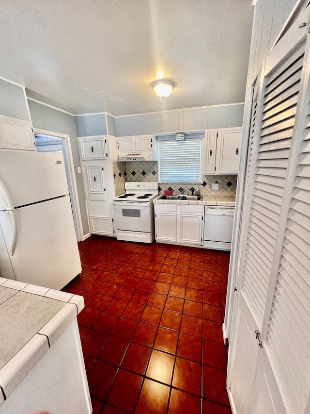 kitchen with white cabinetry, tile counters, dark tile patterned floors, white appliances, and backsplash