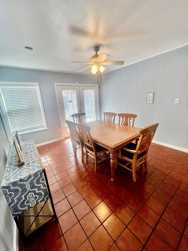 tiled dining area with ceiling fan and wooden walls