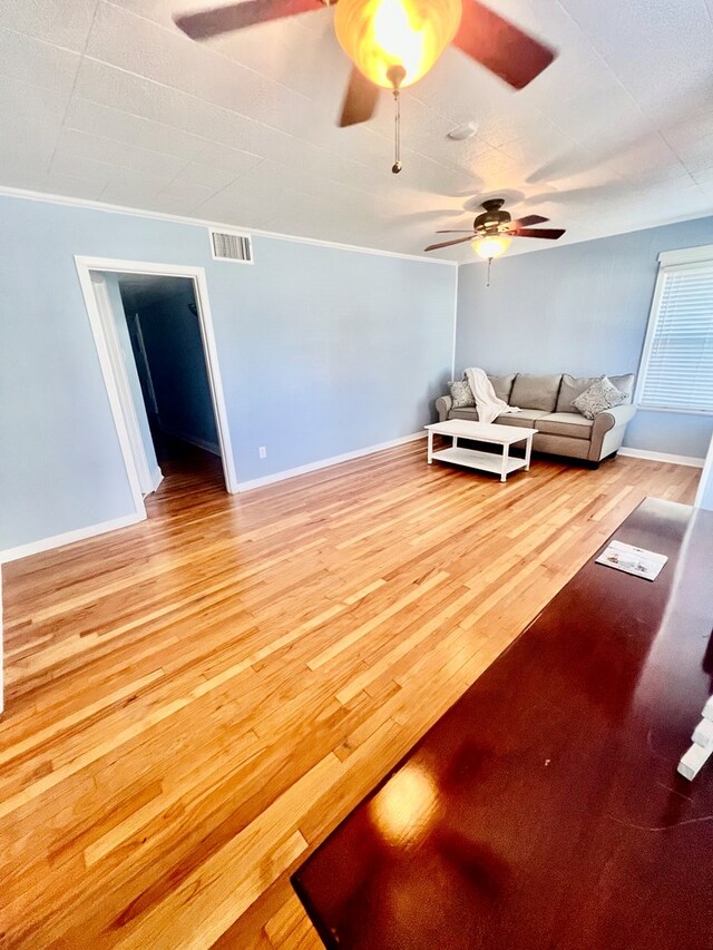 living room featuring ceiling fan, ornamental molding, and wood-type flooring