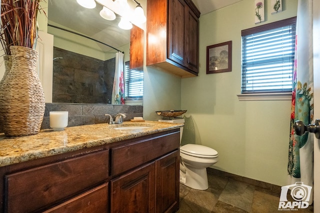 bathroom featuring tasteful backsplash, vanity, toilet, and a healthy amount of sunlight