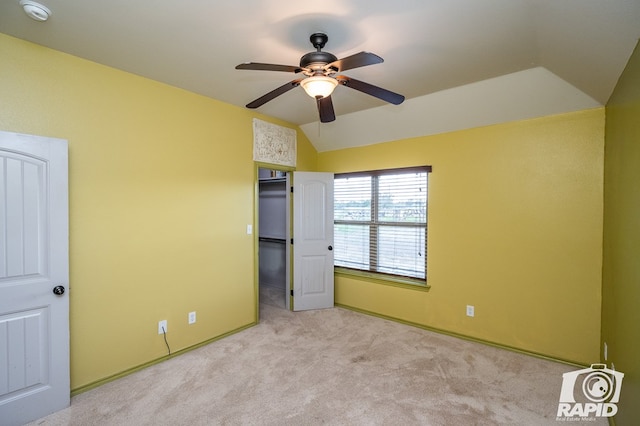 unfurnished bedroom with lofted ceiling, ceiling fan, light carpet, a spacious closet, and a closet