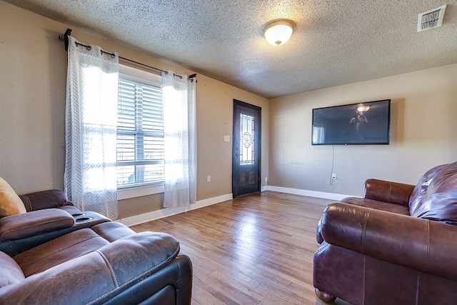 living room featuring light hardwood / wood-style floors and a textured ceiling