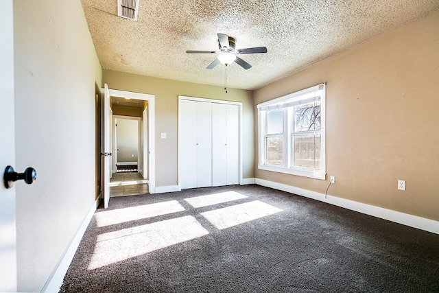 unfurnished bedroom featuring ceiling fan, carpet floors, a closet, and a textured ceiling