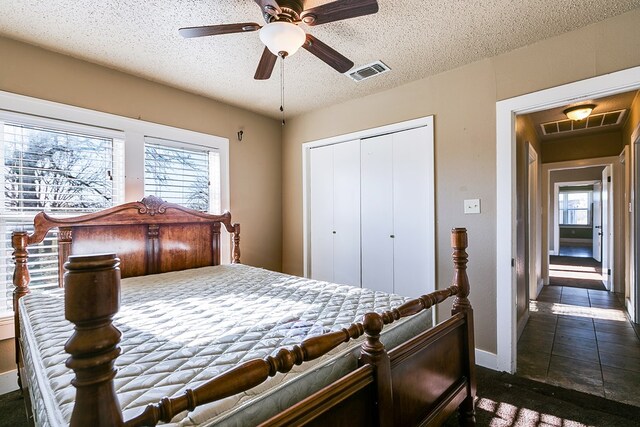 bedroom with multiple windows, ceiling fan, a closet, and a textured ceiling