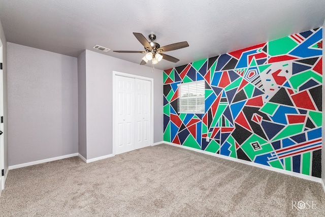 unfurnished bedroom featuring carpet flooring, a textured ceiling, ceiling fan, and a closet