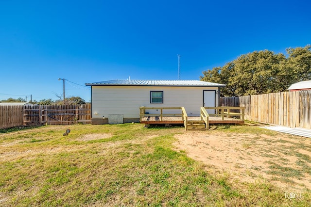 back of property featuring a deck and a lawn