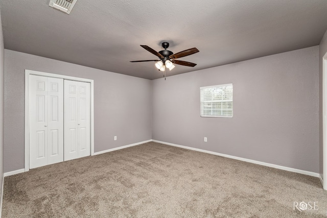 unfurnished bedroom with carpet flooring, a textured ceiling, ceiling fan, and a closet