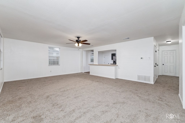 unfurnished living room with ceiling fan, carpet floors, and a textured ceiling