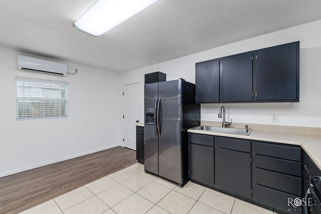 kitchen with light tile patterned floors, sink, a wall mounted AC, a textured ceiling, and stainless steel fridge with ice dispenser