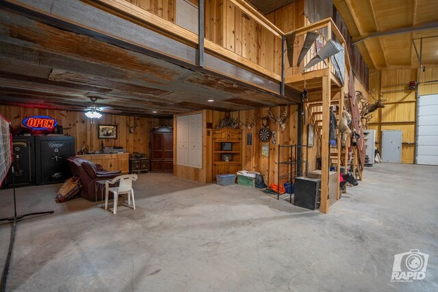 basement with ceiling fan and wood walls