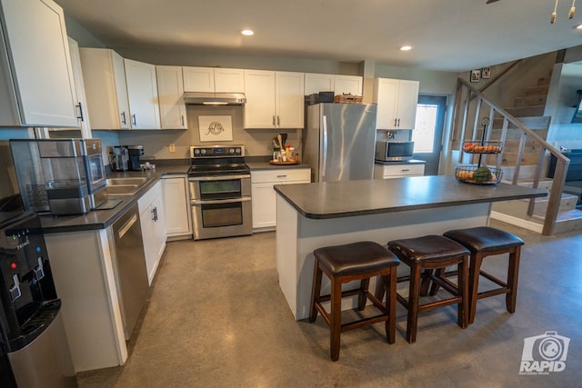 kitchen with white cabinetry, stainless steel appliances, a center island, and a breakfast bar area