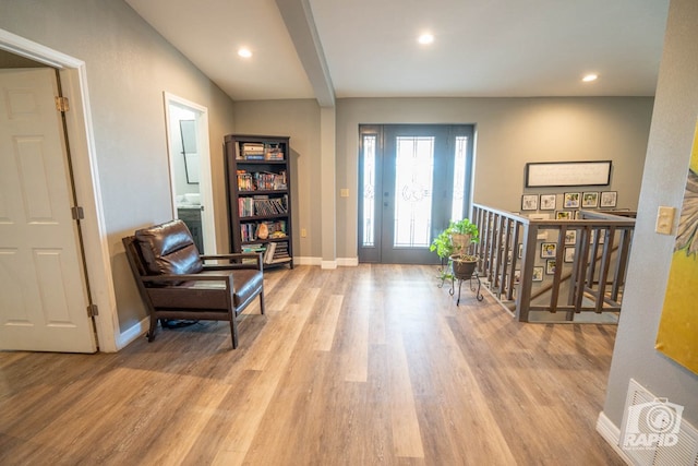 foyer entrance with beamed ceiling and light wood-type flooring