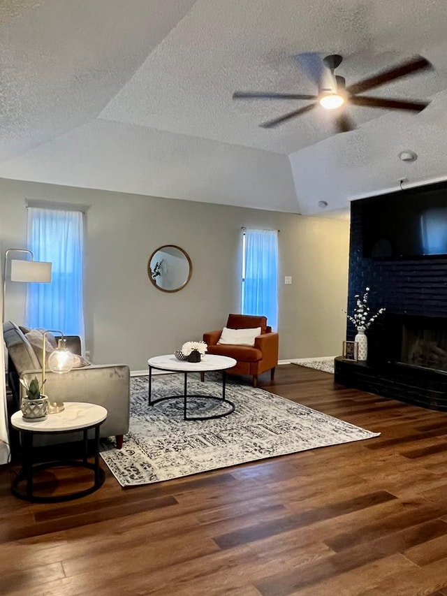 living room featuring ceiling fan, a large fireplace, plenty of natural light, and wood finished floors