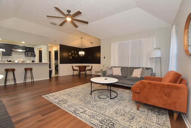 living room featuring vaulted ceiling, visible vents, a textured ceiling, and wood finished floors