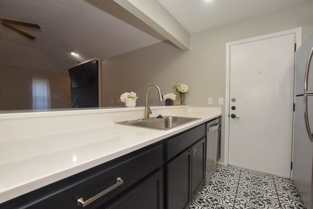 kitchen featuring a sink, light countertops, light tile patterned flooring, stainless steel appliances, and dark cabinets