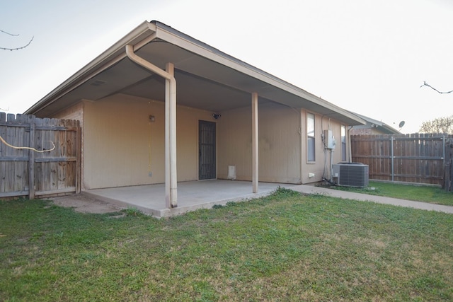 rear view of house featuring a patio area, central air condition unit, and a lawn