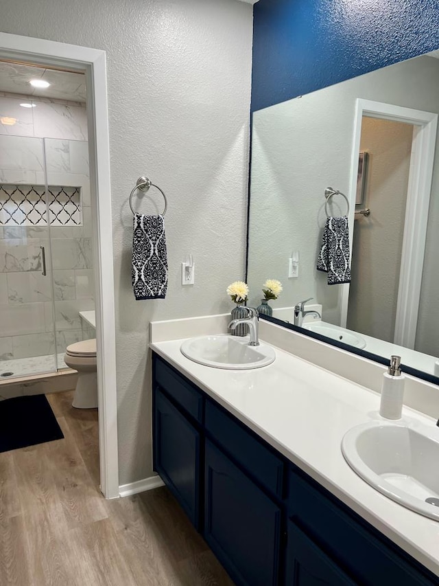 full bathroom featuring toilet, wood finished floors, a stall shower, and a sink