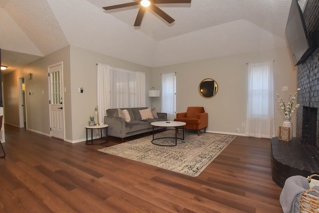 living room featuring lofted ceiling, a fireplace, dark hardwood / wood-style flooring, and a textured ceiling