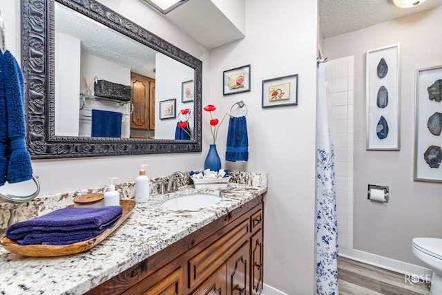 bathroom featuring vanity, wood-type flooring, toilet, and a textured ceiling