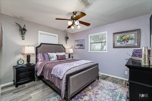 bedroom with ceiling fan, a textured ceiling, and light wood-type flooring