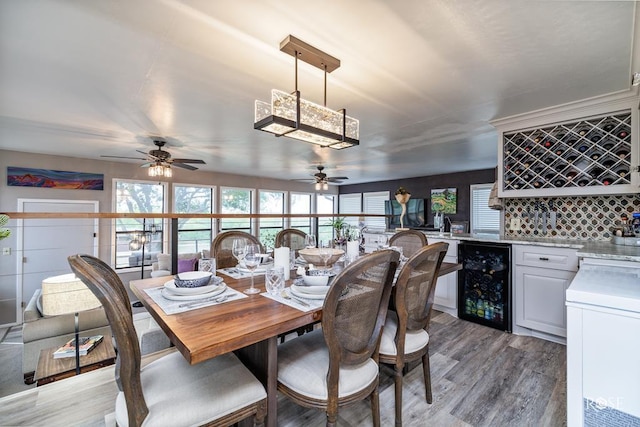 dining space featuring wine cooler, light hardwood / wood-style floors, and indoor bar