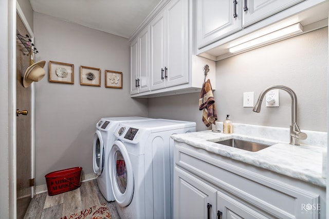 laundry room with sink, hardwood / wood-style floors, washing machine and dryer, and cabinets