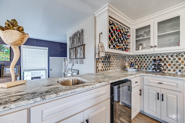 kitchen featuring sink, white cabinets, beverage cooler, decorative backsplash, and light hardwood / wood-style floors