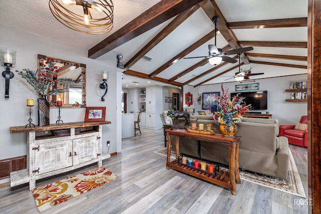 living room featuring vaulted ceiling with beams, wood-type flooring, and a textured ceiling