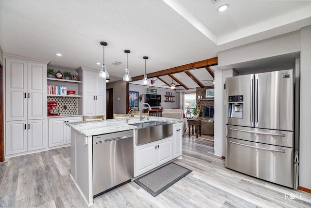 kitchen featuring white cabinetry, an island with sink, hanging light fixtures, light stone counters, and stainless steel appliances