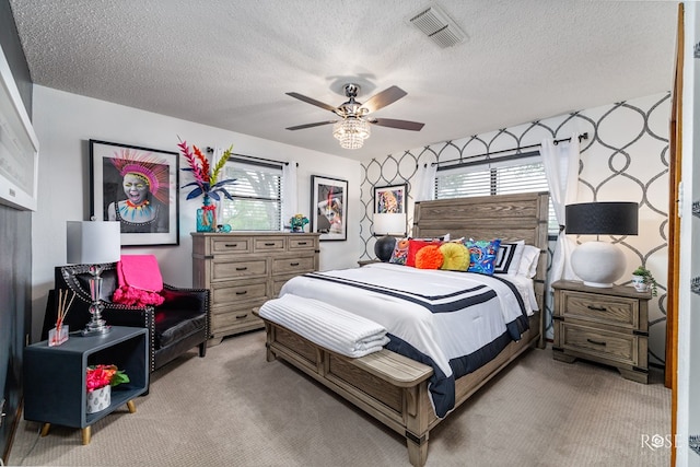 bedroom featuring ceiling fan, light colored carpet, and a textured ceiling