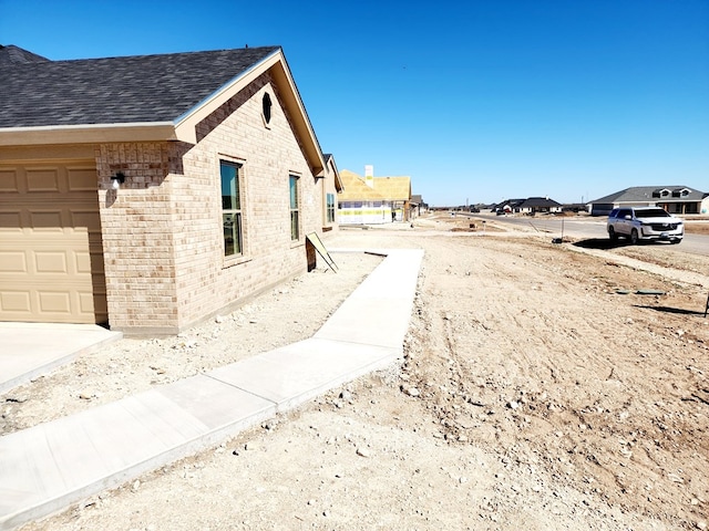 view of property exterior featuring a shingled roof and brick siding