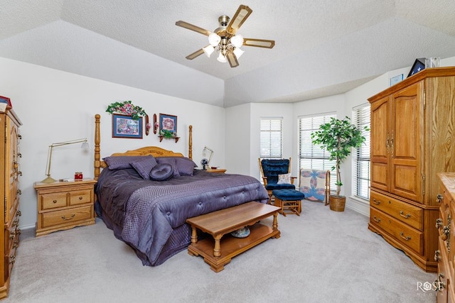 bedroom featuring ceiling fan, vaulted ceiling, a textured ceiling, and light colored carpet