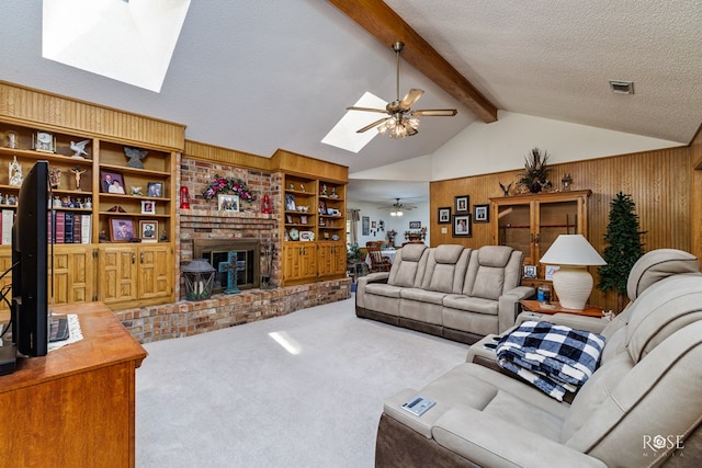 living area with a fireplace, a ceiling fan, carpet flooring, a textured ceiling, and vaulted ceiling with skylight