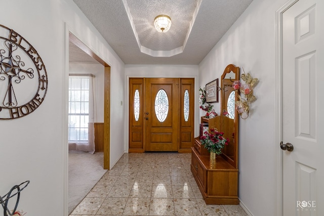 entrance foyer featuring a textured ceiling, light tile patterned floors, baseboards, and light colored carpet