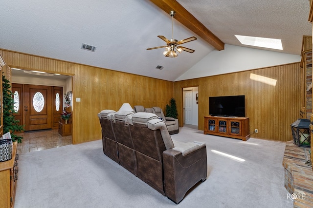 living area featuring lofted ceiling with skylight, visible vents, wooden walls, and carpet flooring