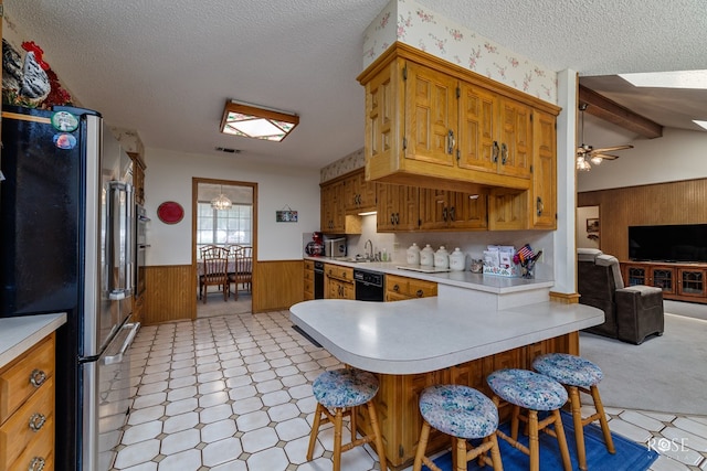 kitchen featuring a wainscoted wall, light countertops, freestanding refrigerator, wood walls, and a sink