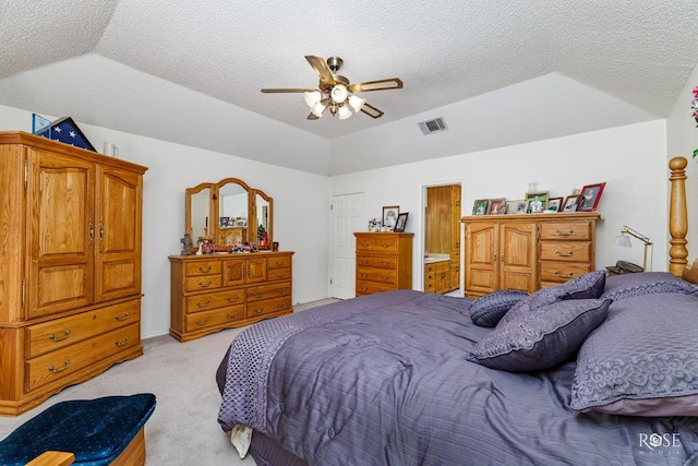 bedroom with light carpet, visible vents, vaulted ceiling, and a textured ceiling