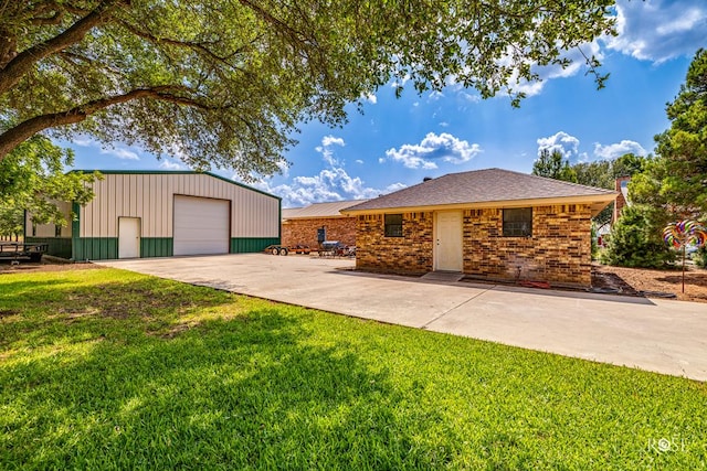 view of front of house featuring an outbuilding, a garage, brick siding, concrete driveway, and a front yard