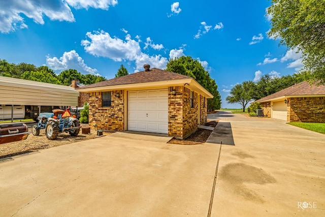 view of side of property featuring a garage, brick siding, and an outbuilding