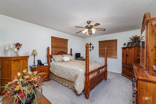 bedroom featuring light carpet, ceiling fan, and a textured ceiling