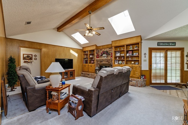 living room featuring a textured ceiling, wooden walls, light carpet, a wainscoted wall, and lofted ceiling with skylight