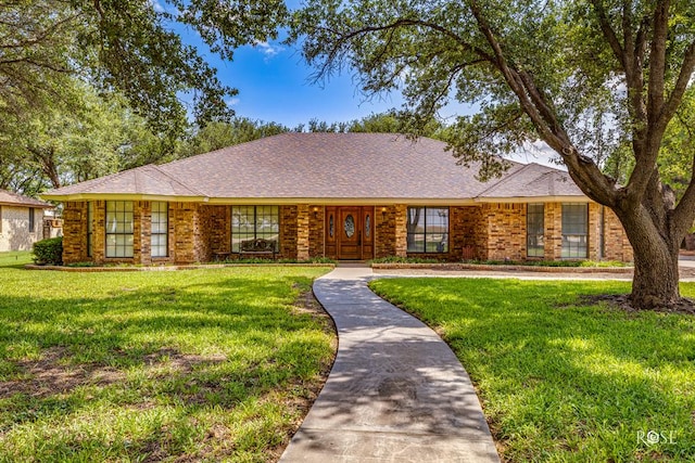 ranch-style house featuring brick siding, a front yard, and a shingled roof