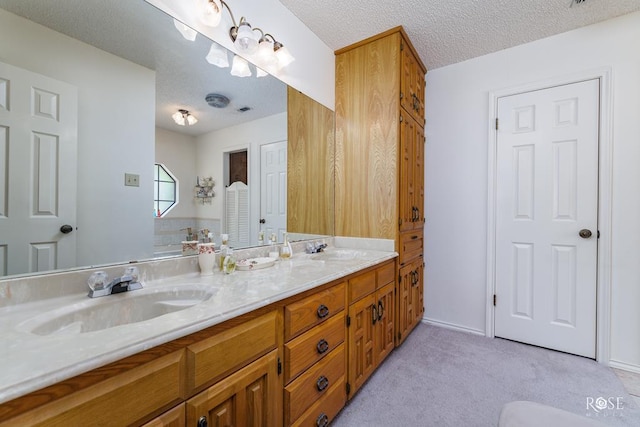 bathroom with a textured ceiling, double vanity, and a sink